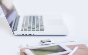 A white laptop on a white table.