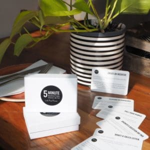 A Marketing Deck: 5 Minute Marketing Ideas table adorned with cards and a potted plant.