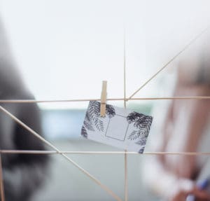 A woman is holding a business card on a peg board.