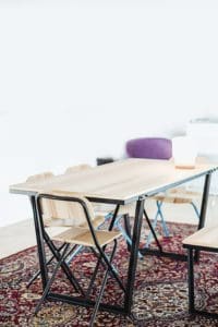 A table and chairs in a room with a rug.