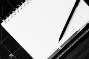 A monochrome image featuring a notebook and pen, evoking the concept of a business plan.