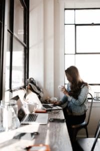 A woman sitting at a desk with a laptop and a cup of coffee.