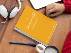 A person sitting at a desk with a notebook and headphones.