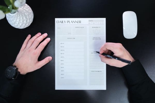 A man is using Time Blocking Planning Sheets to organize his schedule in his planner.