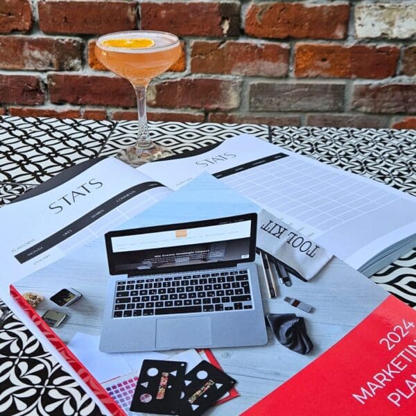 The Marketing Planner - 2024 Edition sits on a table next to a cocktail, representing the perfect setting for a marketing planner.