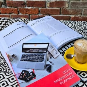 A coffee cup and The Marketing Planner - 2024 Edition on a table.