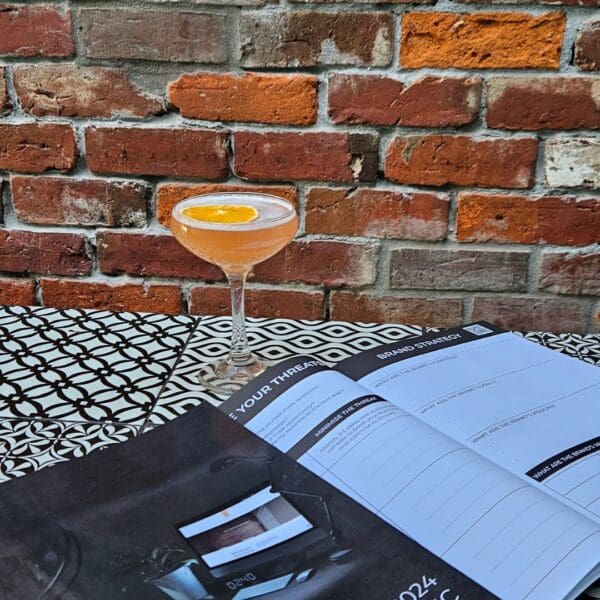 A cocktail is sitting on a table next to The Strategic Planner.