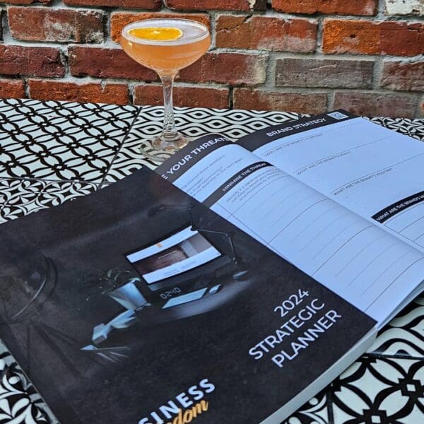 A 2024 Planning Bundle with a cocktail on it next to a brick wall.