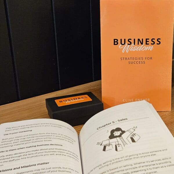 A book on Business Wisdom: Strategies for Success next to an orange book on a table.